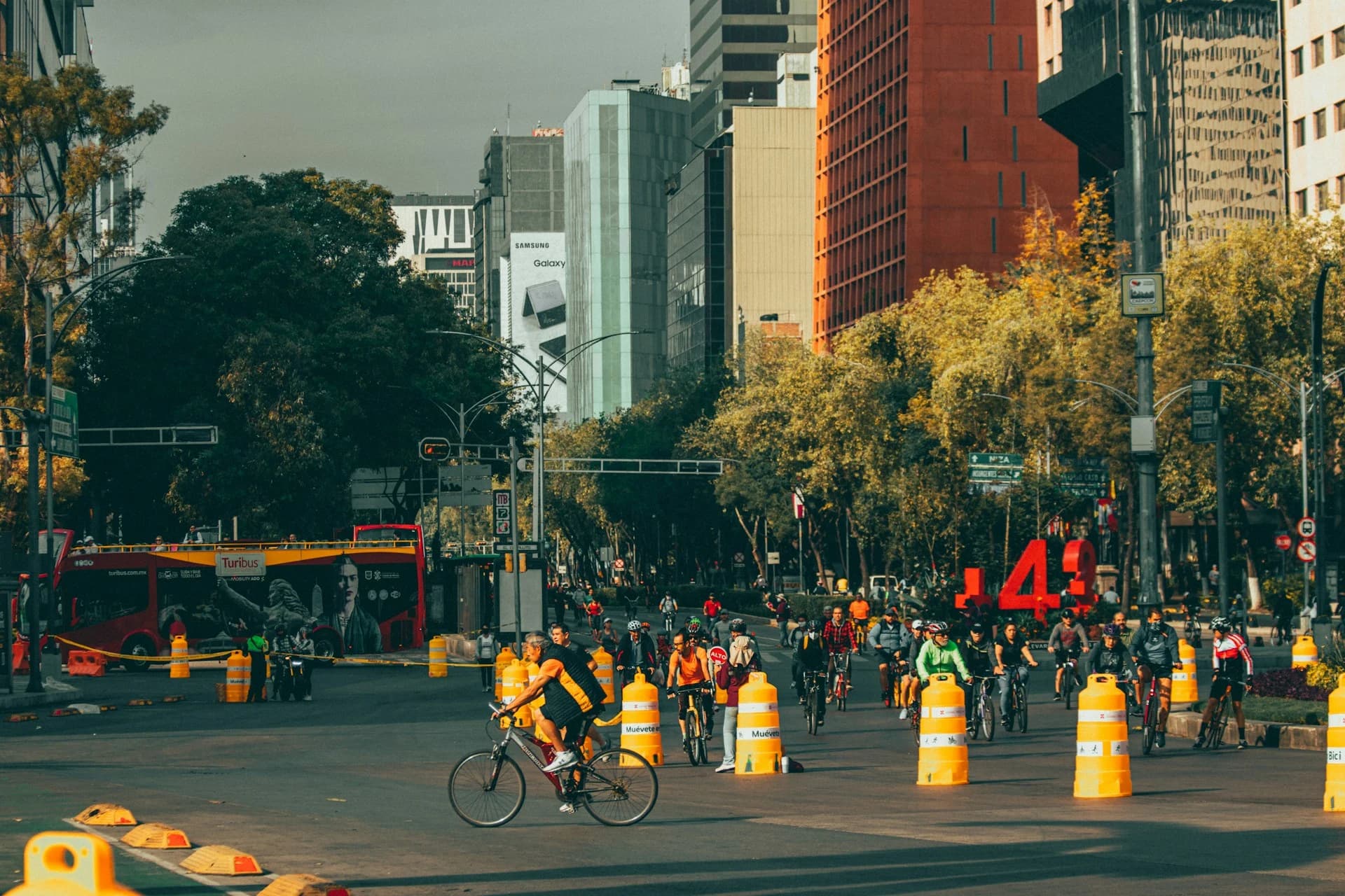 A small group of cyclists riding along Paseo de la Reforma in Mexico City with the Angel of Independence behind them