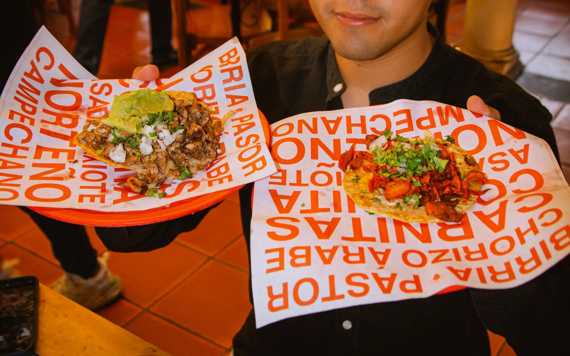 A guide handing out tacos al pastor at a street stand on a Mexico City food tour at night