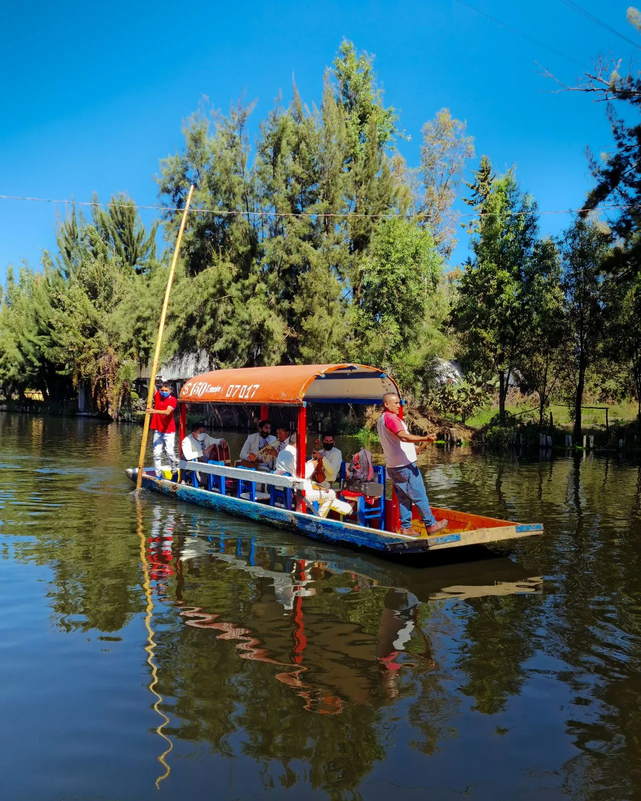 A group of people enjoying a boat ride on a trajinera boat in the Xochimilco canals, Mexico City